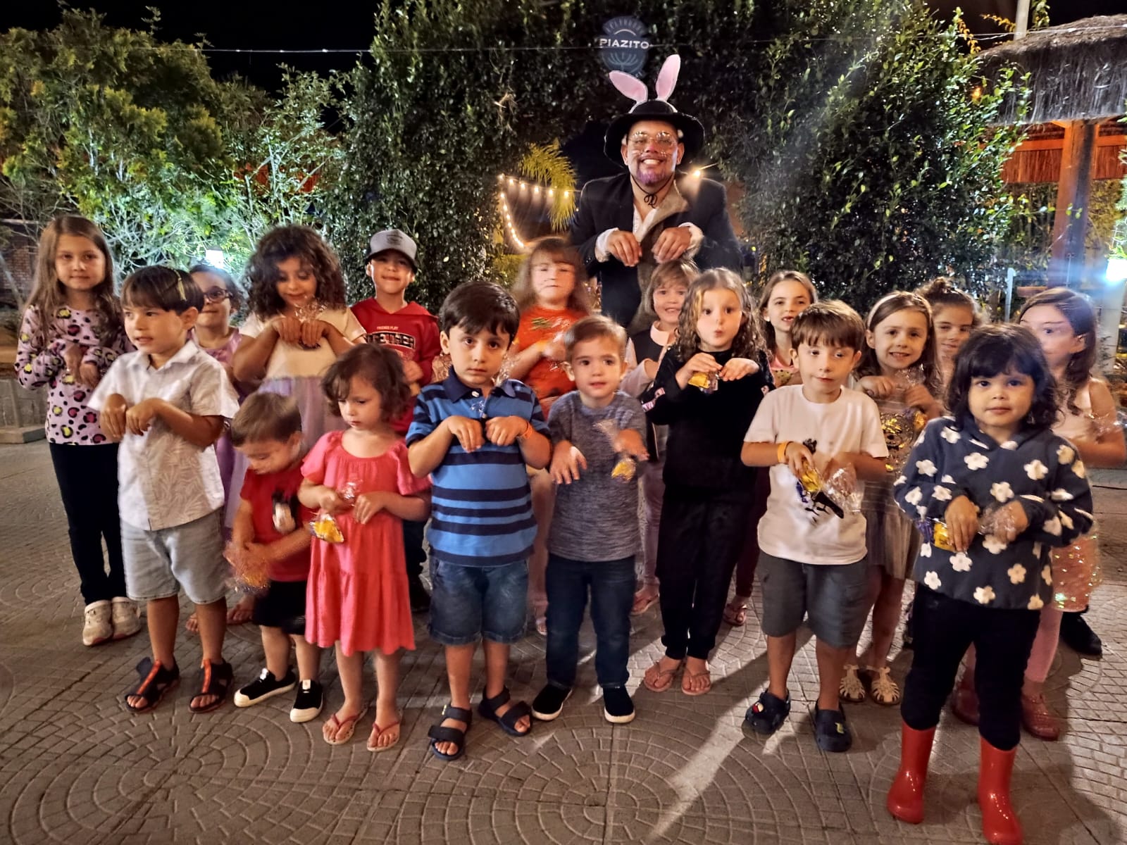 Crianças em evento noturno com recreador fantasiado de coelho