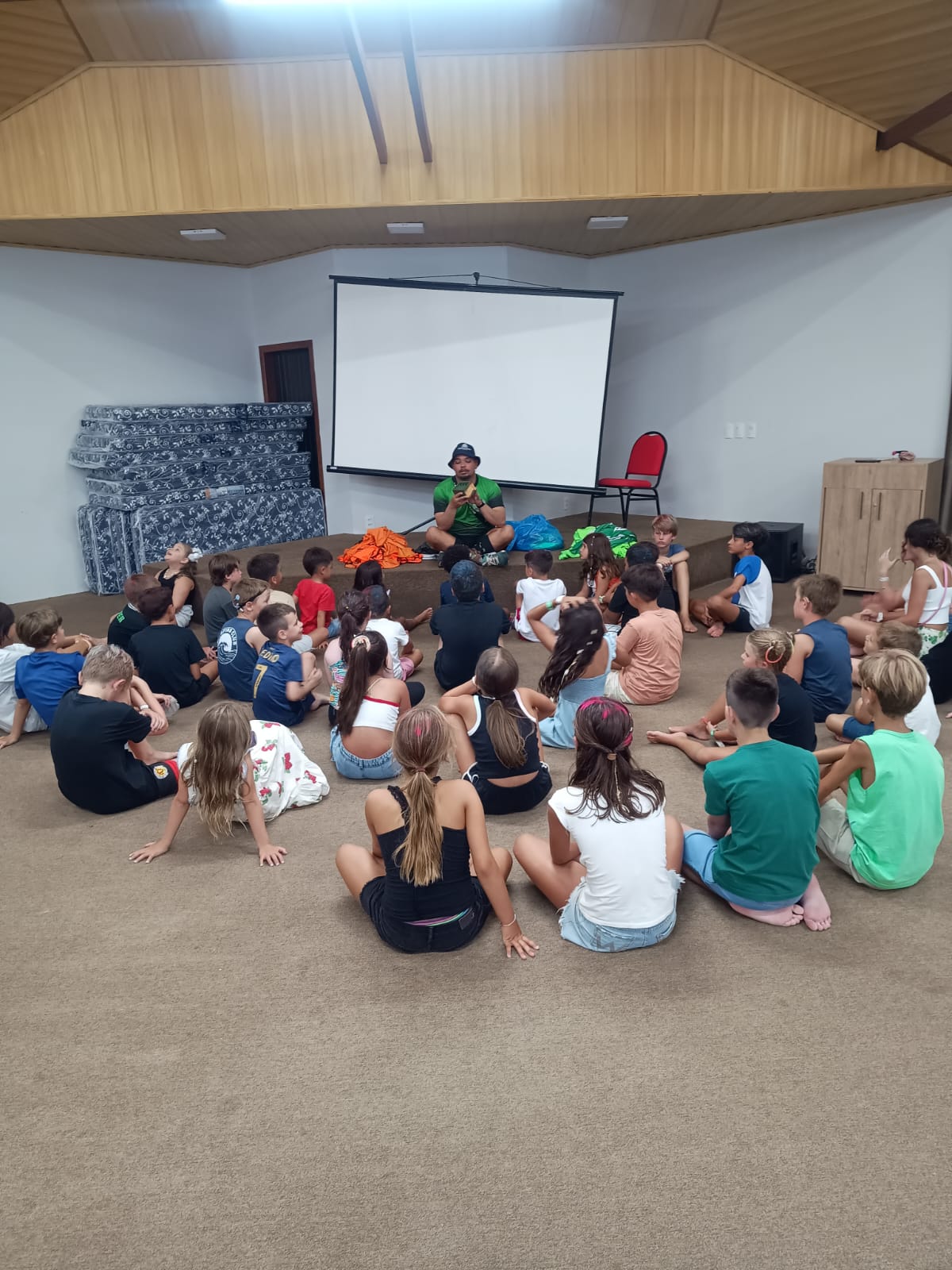 Monitor explicando dinâmica para crianças sentadas em roda