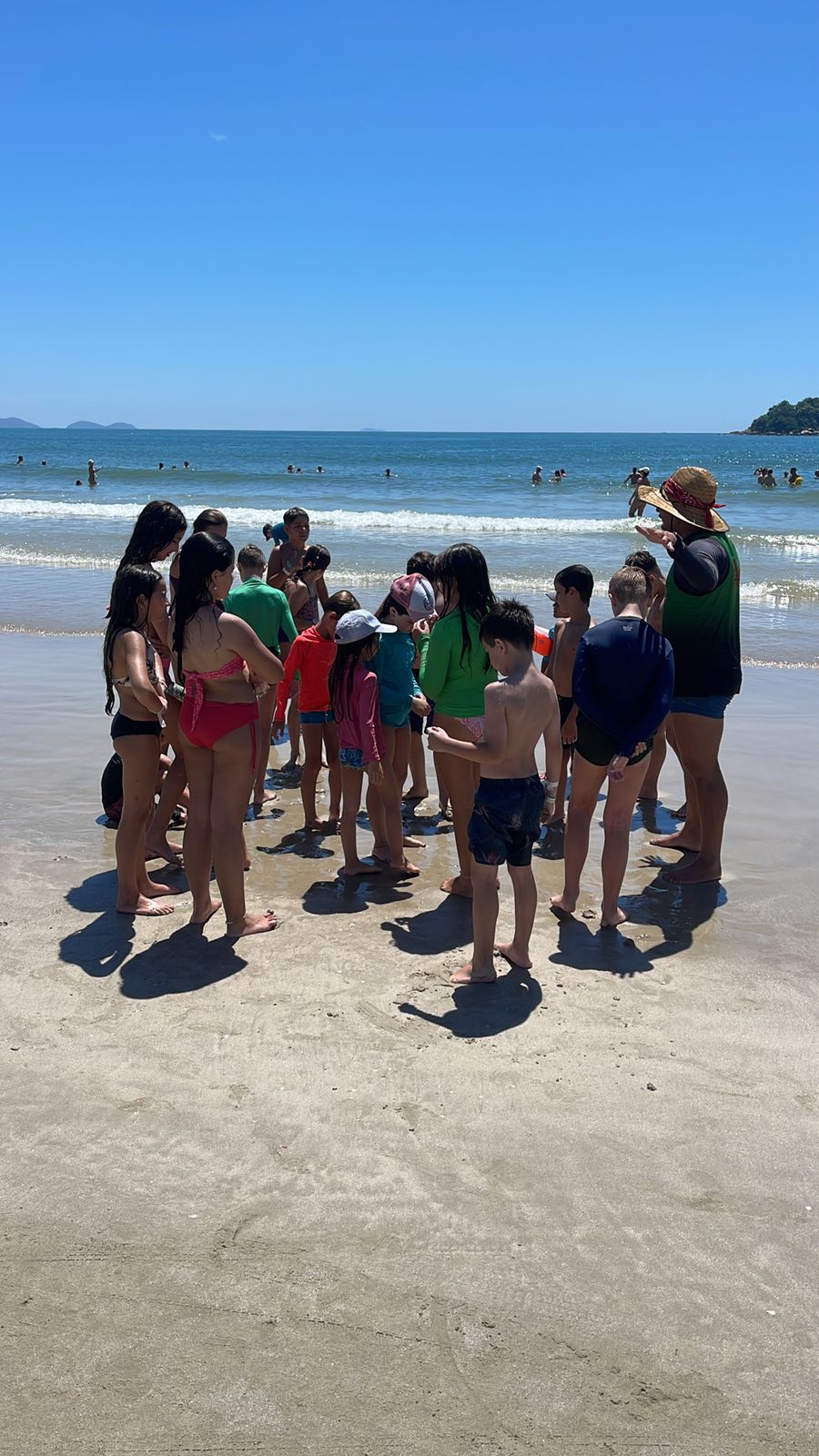 Crianças e recreadora em atividade na praia